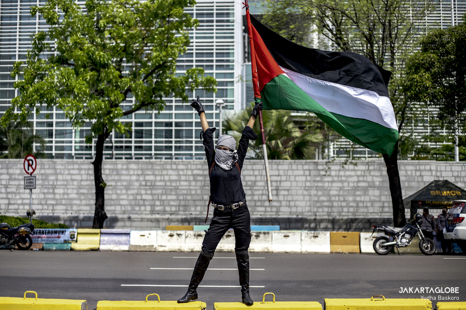 A woman waves the Palestinian flag during a protest against Israel in front of the US Embassy building in Central Jakarta on May 18, 2021. (JG Photo/Yudha Baskoro)