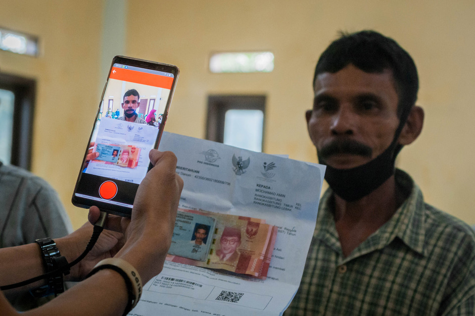 A man has the picture of his face taken by an officer at Pos Indonesia in Lebak, Banten, as part of an authentication process for his social benefit disbursement, on Feb 18, 2022. (Antara Photo/Muhammad Bagus Khoirunas)