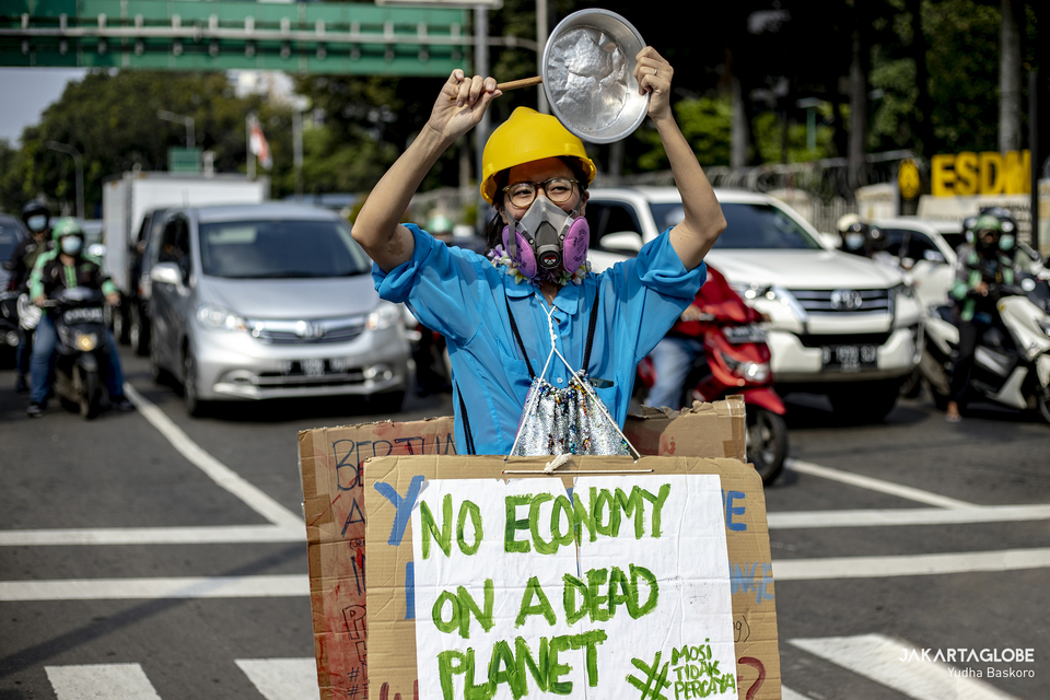 An environmental activist ring a noisy instrument during a protest against climate change in front of the Arjuna Wijaya horse statue in Central Jakarta on June 4, 2021. (JG Photo/Yudha Baskoro)