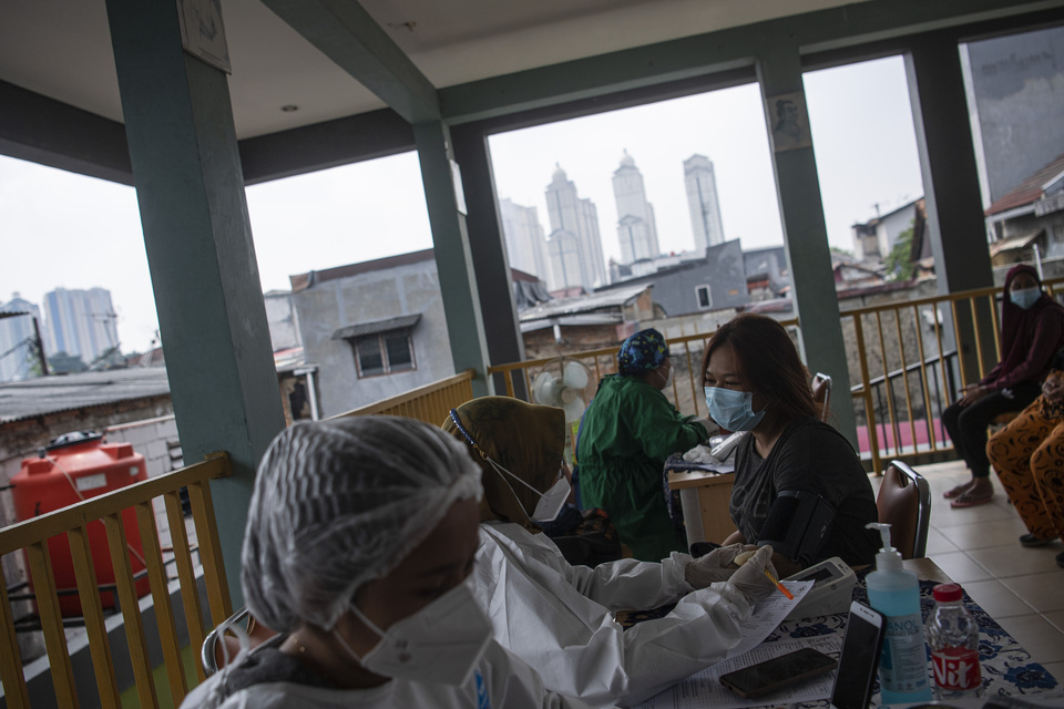 A medical worker examines a woman before administering her Covid-19 vaccine shot in Bandar Kemayoran, North Jakarta, on Saturday. (Antara Photo/Sigid Kurniawan)