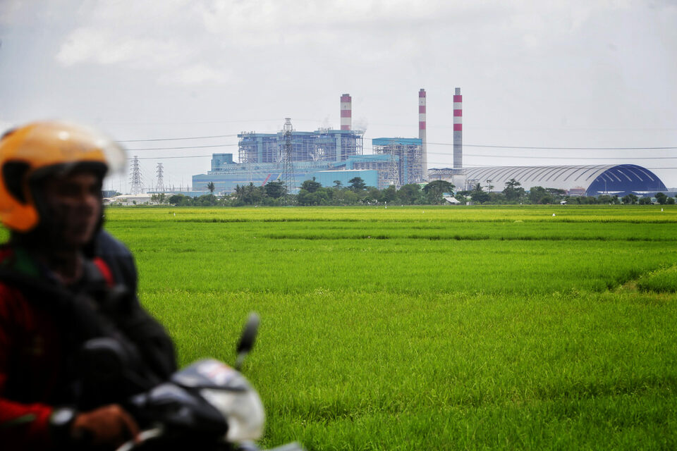 A man rides his motorcycle with the background of a coal-fired power plant in Tangerang district, Banten, on April 27, 2020. (Beritasatu Photo/Ruht Semiono)