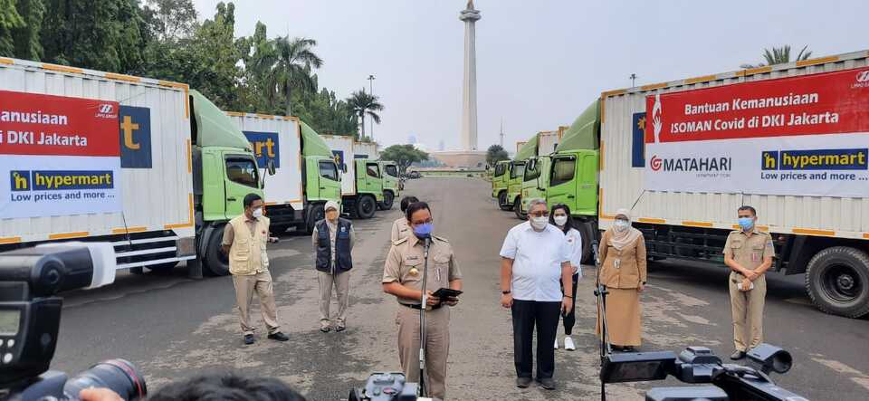 Jakarta Governor Anies Baswedan, center, receives relief supplies donated by major retailers Hypemart and Matahari Department Store at the National Monument Square in Central Jakarta on July 19, 2021. (Beritasatu Photo)