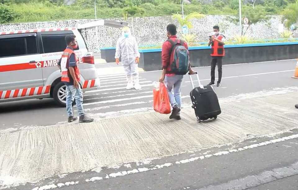 DW, pictured in the red jacket above, walks toward a team that will escort him home for mandatory self-quarantine from Sultan Babullah Airport in Ternate North Maluku on Sunday. (B1 Photo)