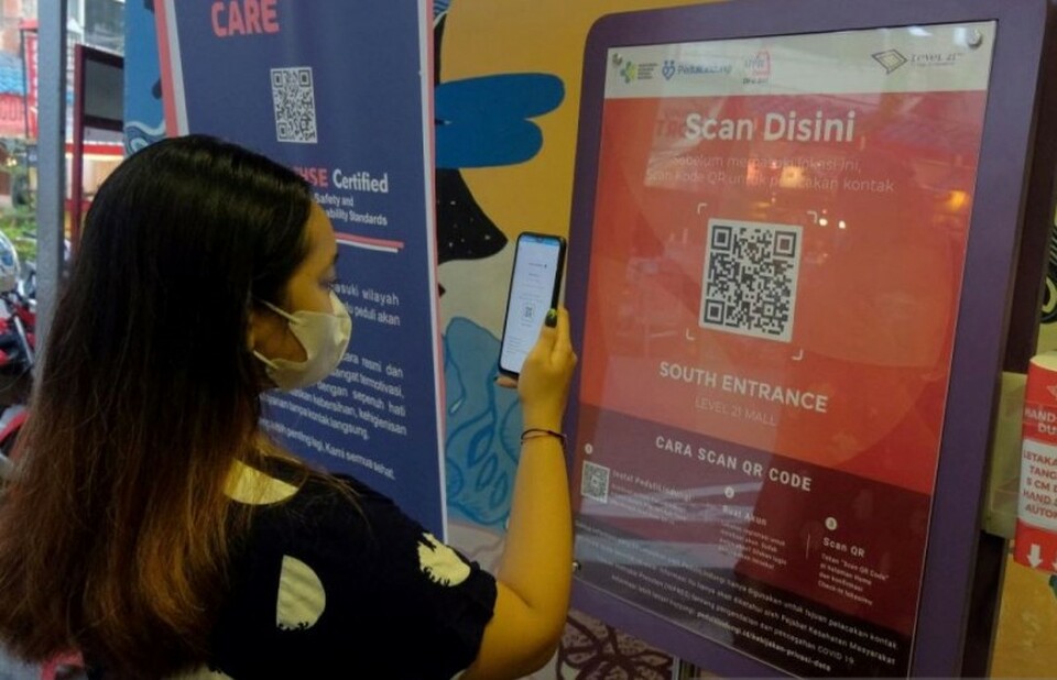 A woman scans the QR code using the Peduli Lindungi app to show her vaccination status before entering a shopping mall in Denpasar, Bali on August 20, 2021. (Antara Photo)