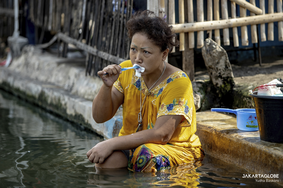 A woman brushes her teeth and bathes in the Cilemahabang River in Bekasi, West Java on September 8, 2021. (JG Photo/Yudha Baskoro)