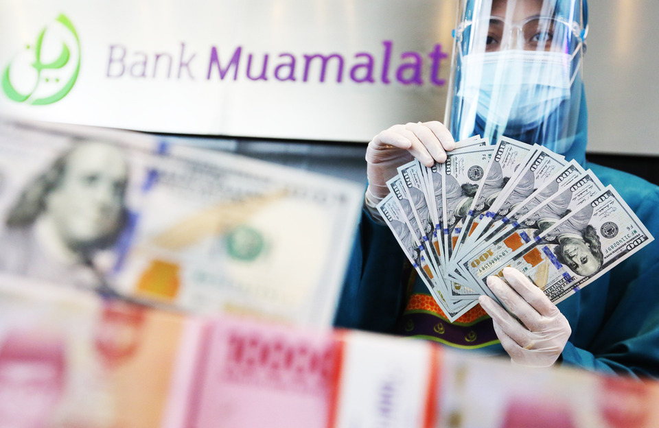 A Bank Muamalat teller is counting U.S. bank notes in Jakarta. (Uthan A. Rachim)