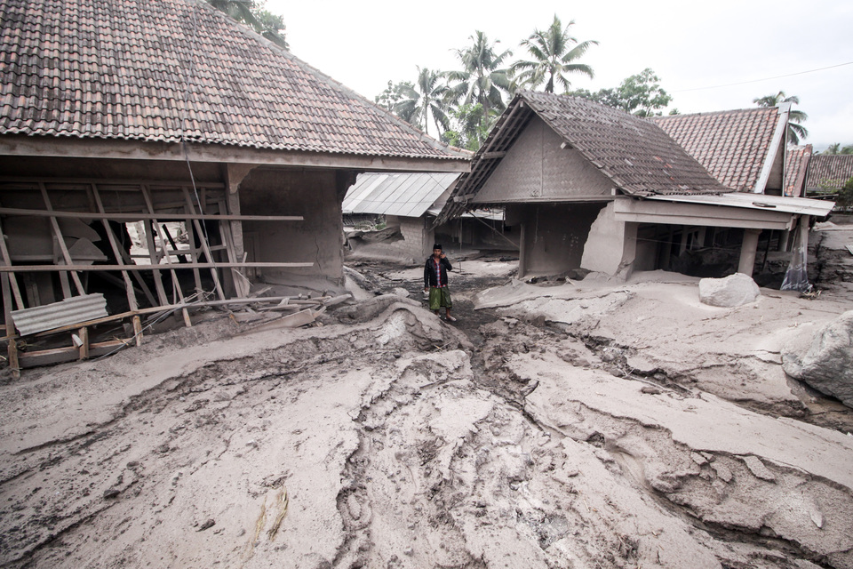 A villager walks past homes destroyed by volcanic debris in Sumber Wuluh Village in the East Java district of Lumajang, December 5, 2021. The village is located on the slope of Mount Semeru that erupted a day earlier. (Antara photo/Umarul Faruq)