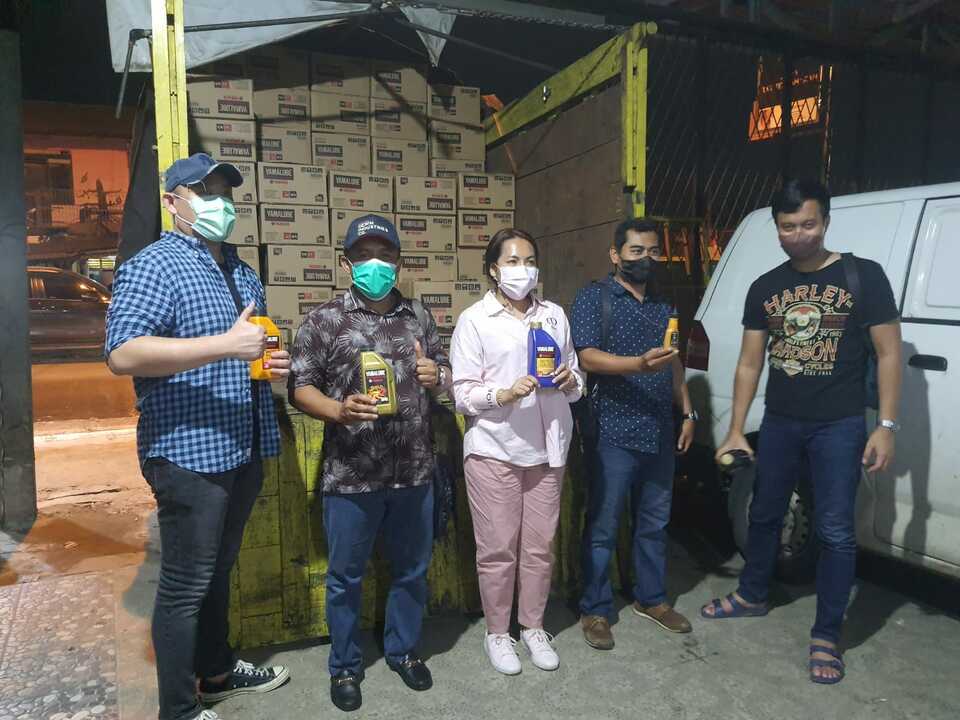 Police investigators in plain clothes pose for a photo in front of bottles of fake engine oil seized during a raid in Tangerang, December 11, 2021. (Beritasatu Photo/Chairul Fikri)