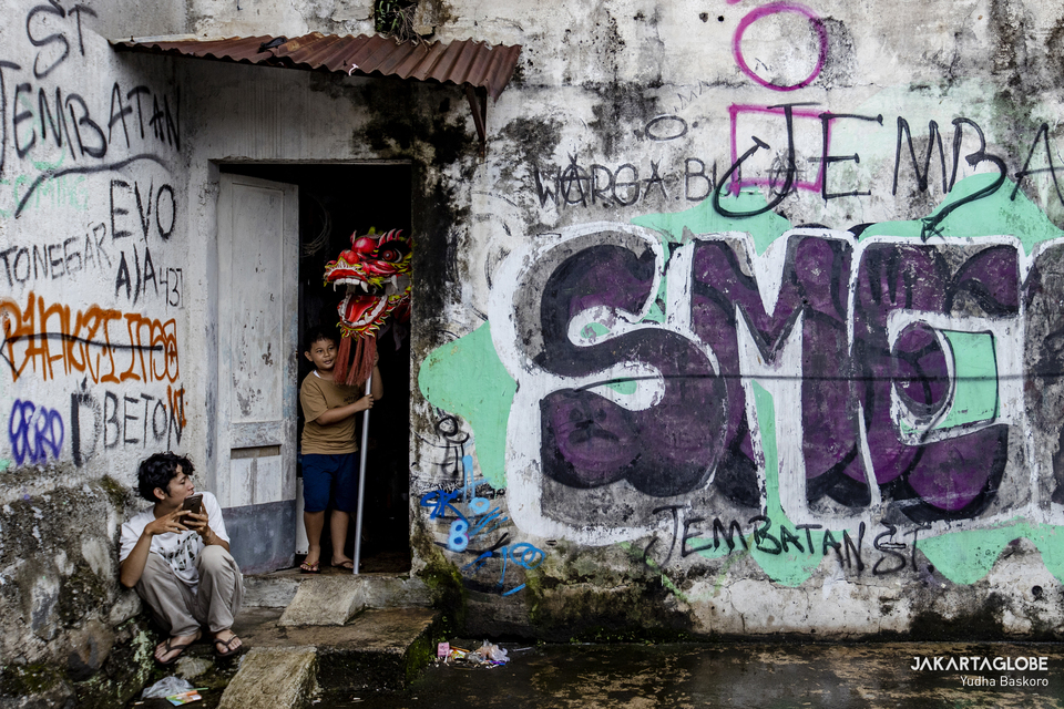 A child carries the head of a giant dragon puppet inside an abandoned factory building in Bogor, West Java on January 15, 2022. (JG Photo/Yudha Baskoro)