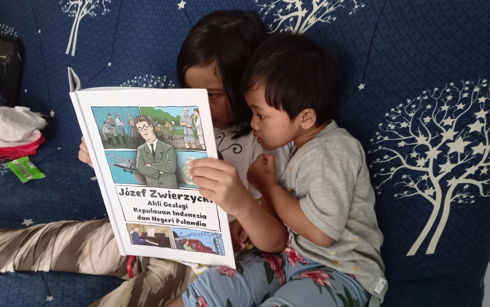 Two children look into a comic book telling the story of Polish geologist Jozef Zwierzycki in Tangerang, Banten, on January 22, 2022. (Jakarta Globe)