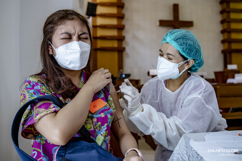 A woman reacts as she receives her booster dose of the Covid-19 vaccine at an HKBP church in Menteng, Central Jakarta on February 3, 2022. (JG Photo/Yudha Baskoro)