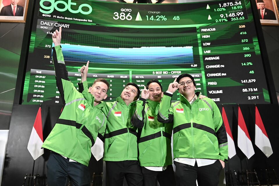 Standing left to right, GoTo Group president Patrick Cao, co-founder William Tanuwijaya, group CEO Andre Soelistyo, and co-founder Kevin Aluwi pose for a photograph under a giant screen after the company's shares trading debut on the Indonesia Stock Exchange in Jakarta on Monday. (Photo courtesy of ambar puspa galuh)