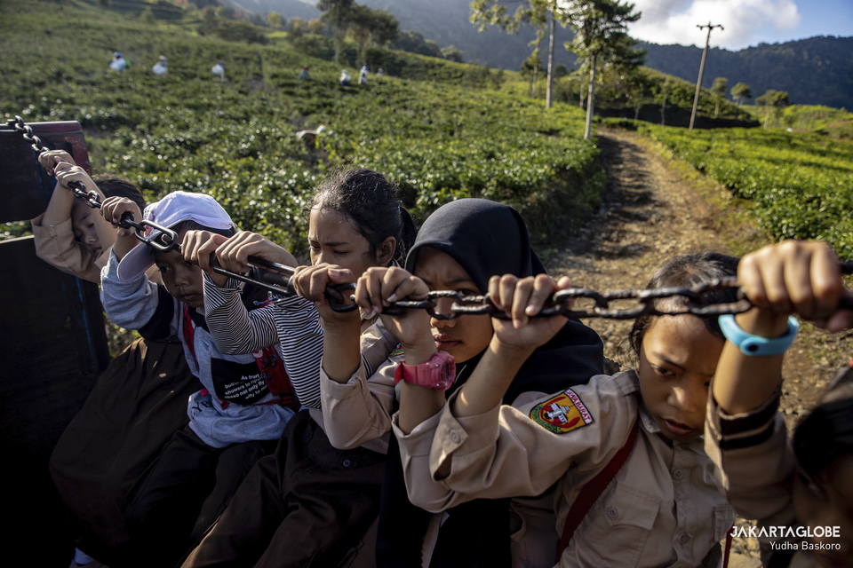 Students hold onto a chain as they hitchhike a truck to go to school at the Tugu Utara village in Bogor, West Java on June 2, 2022. (JG Photo/Yudha Baskoro)