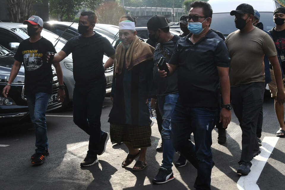 Khilafatul Muslimin leader Abdul Qadir Baraja, center, is escorted by police officers in plain clothes at the Jakarta Police headquarters on June 7, 2022. (Antara Photo/Aditya Pradana Putra)
