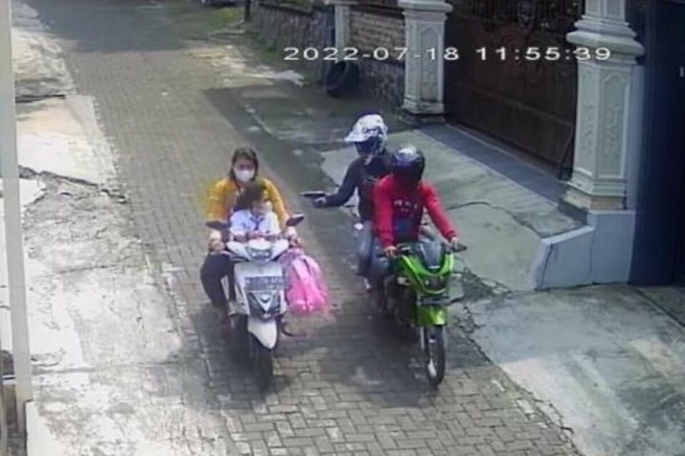 In this screen capture from video footage obtained by the Central Java Police, a man on the back of a motorcycle points a gun at Rina Wulandari in an apparent murder attempt in Semarang, Central Java, on July 18, 2022. (Videography)
