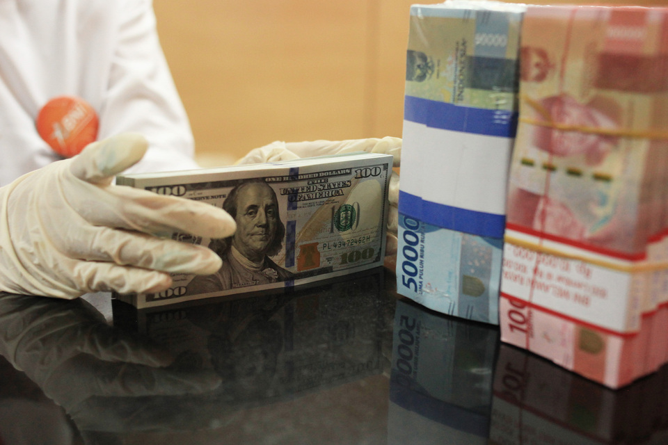 An employee counts US dollars and rupiah at state-owned lender Bank Negara Indonesia's Melawai branch office in Jakarta on Aug 18, 2022. (Antara Photo/Reno Esnir)