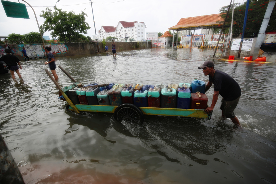 A clean water trader pushes his cart across the tidal flood that inundated Jalan Lodan Raya, Pademangan, in North Jakarta on July 12, 2022. (B1 Photo/Joanito De Saojoao)