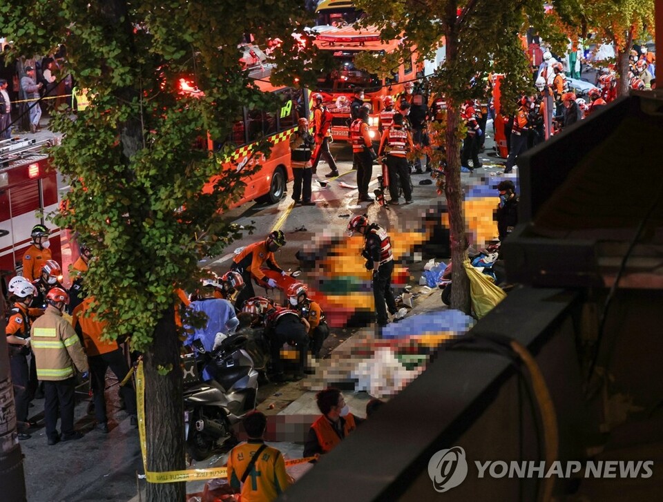 Rescuers attend to victims on a street in Seoul's Itaewon district on Oct. 30, 2022, after about 50 people were reported to be in cardiac arrest from a stampede during Halloween parties the previous day. (Yonhap News Agency)