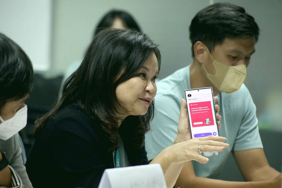 BCA Digital President Director Lanny Budiati, center, shows digital bank app Blu on her cellphone during a visit to B-Universe newsroom in Jakarta on November 16, 2022. (Joanito De Saojoao)