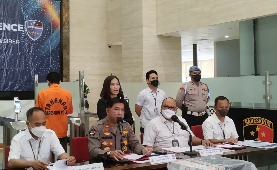The cybercrime directorate of the National Police holds a news conference to brief a fraud case involving deceptive websites in Jakarta on November 23, 2022. The suspect in an orange detainee suit, is presented in the conference. (BeritaSatu/Stevani Wijaya)