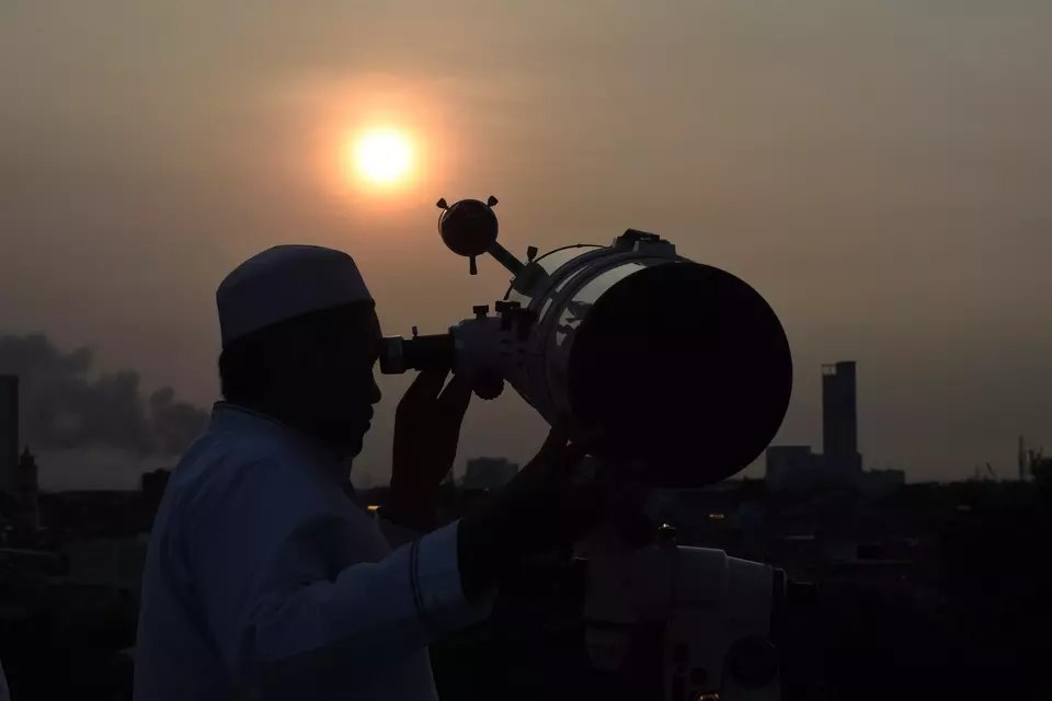 A man looks into an optical telescope to look for the sighting of the crescent Moon that determines the first day of Ramadan at Al-Musyari