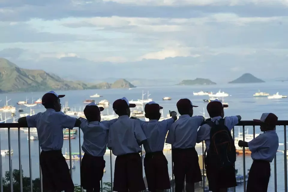 Indonesian students stand in front of a view of the Labuan Bajo marina, gateway to Komodo National Park, Labuan Bajo, East Nusa Tenggara province, Indonesia, Monday, May 8, 2023. (AP Photo/Achmad Ibrahim)