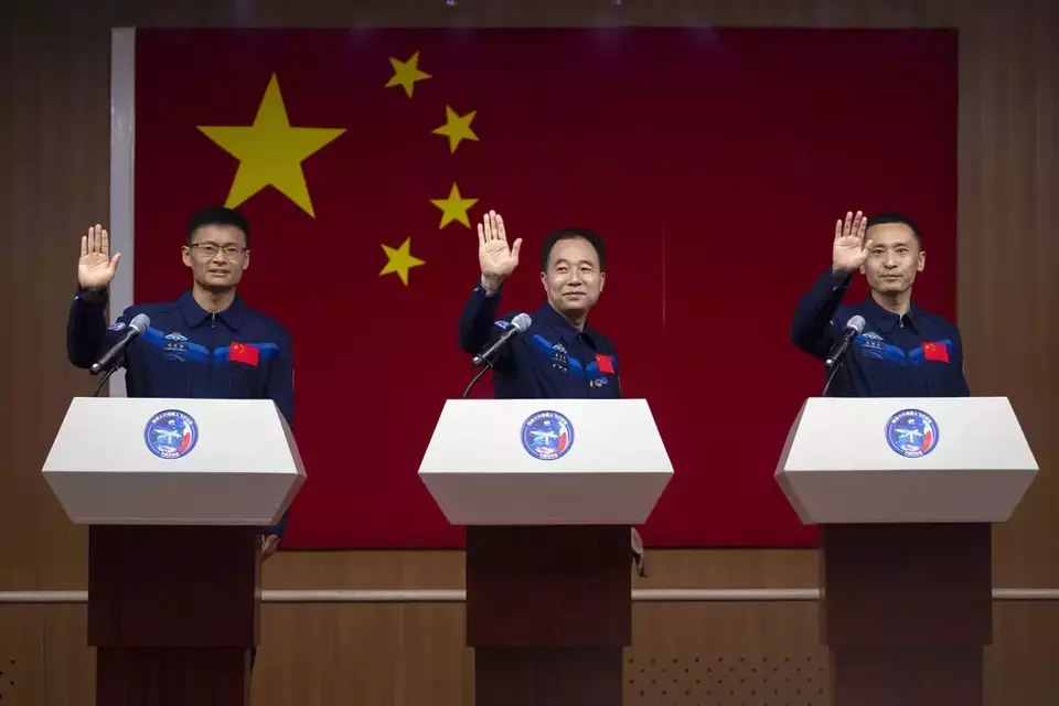 Chinese astronauts for the upcoming Shenzhou-16 mission, from left, Gui Haichao, Jing Haipeng, and Zhu Yangzhu wave as they stand behind glass during a meeting with the press at the Jiuquan Satellite Launch Center in northwest China on Monday, May 29, 2023. (AP Photo/Mark Schiefelbein)