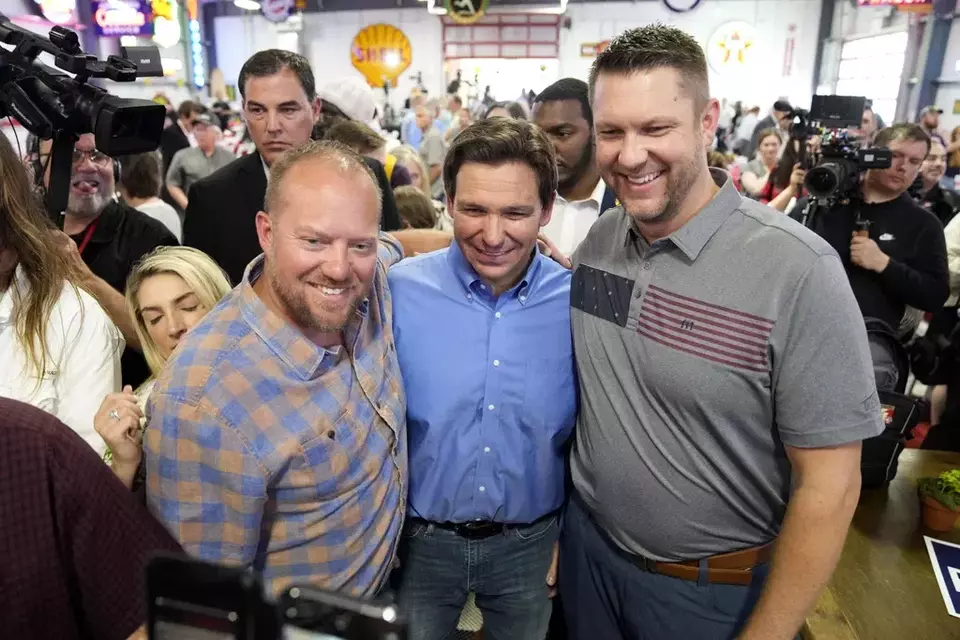 FILE - Florida Governor Ron DeSantis, center, poses for a photo with audience members during a fundraising picnic for Rep. Randy Feenstra, R-Iowa, May 13, 2023, in Sioux Center, Iowa. (AP Photo/Charlie Neibergall)