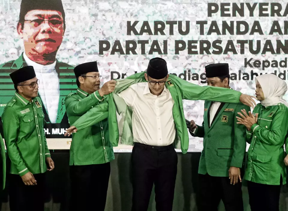 Sandiaga Uno, center, puts on the PPP jacket after officially becoming a member of the United Development Party (PPP) during a ceremony in Menteng, Jakarta, Wednesday, June 14, 2023. (Joanito De Saojoao)