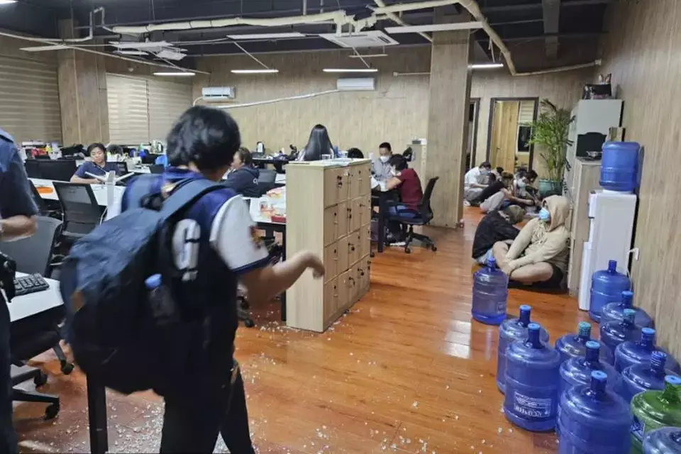 In this handout photo provided by the Philippine National Police Anti-Cybercrime Group, a police officer walks inside one of the offices they raided in Las Pinas, Philippines on Tuesday, June 27, 2023. (Philippine National Police Anti-Cybercrime Group via AP)