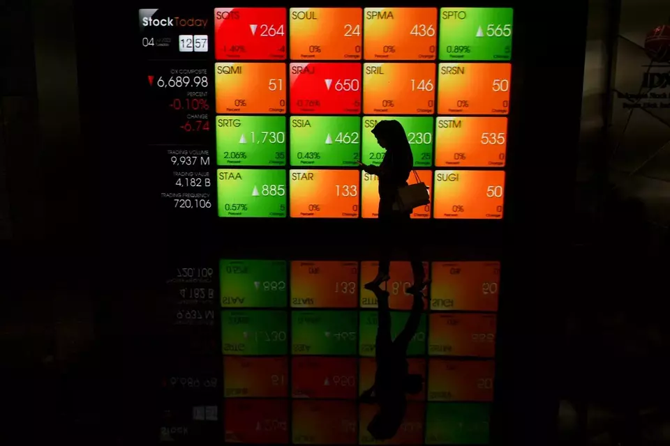 A worker passing by a screen, showing the fluctuation of stocks in IDX, Jakarta, July 4, 2023. (Antara Photo/Hafidz Mubarak A)