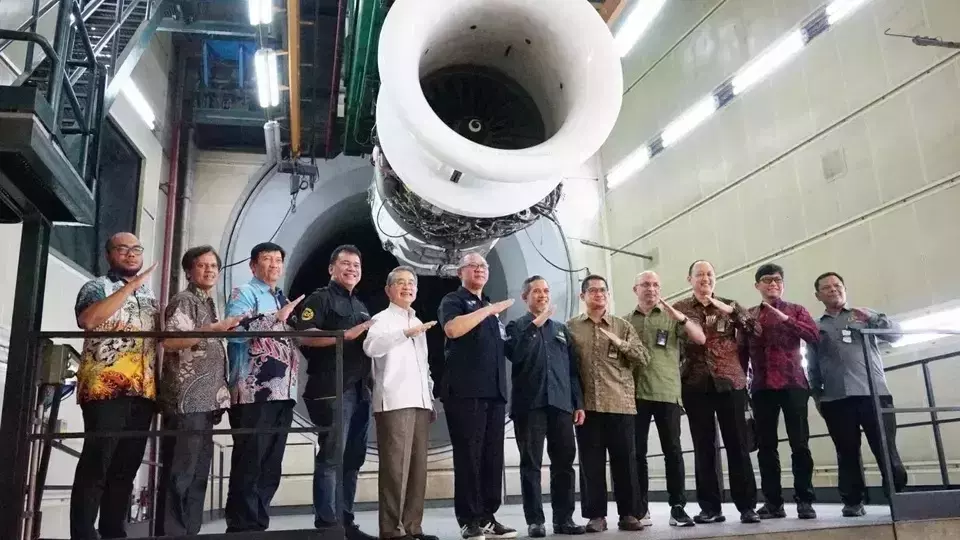Government officials and Garuda Indonesia executives pose for a photo in front of a plane engine that underwent a biofuel mix trial on July 26, 2023. (Handout)
