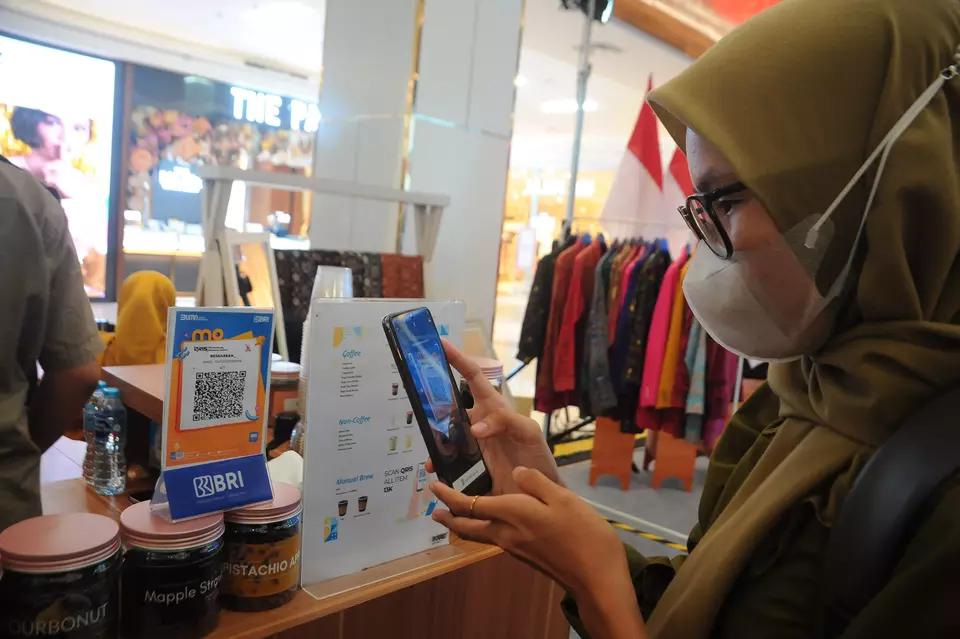 A woman scans QRIS to shop in Palembang, South Sumatera, on August 15, 2023. (Antara Photo/Feny Selly)