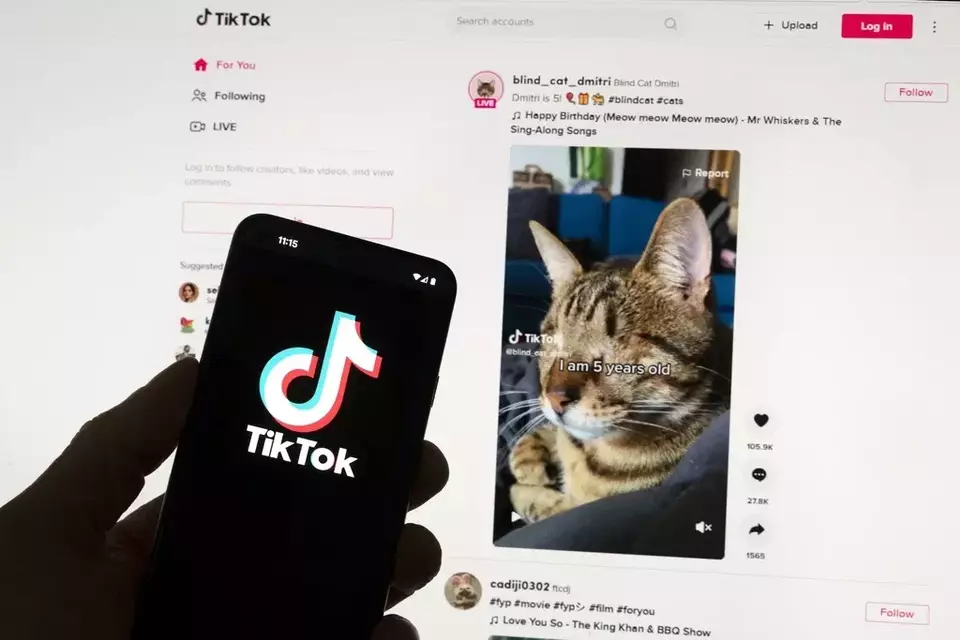 The TikTok logo is seen on a mobile phone in front of a computer screen which displays the TikTok home screen, Saturday, March 18, 2023, in Boston. (AP Photo/Michael Dwyer)