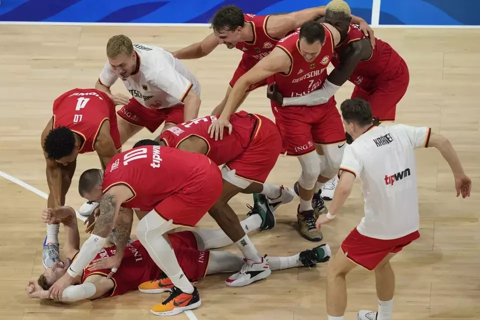 Germany guard Andreas Obst lays on the ground as teammates celebrate after winning against the United States in a Basketball World Cup semi-final game in Manila, Philippines, Friday, Sept. 8, 2023. (AP Photo/Aaron Favila)