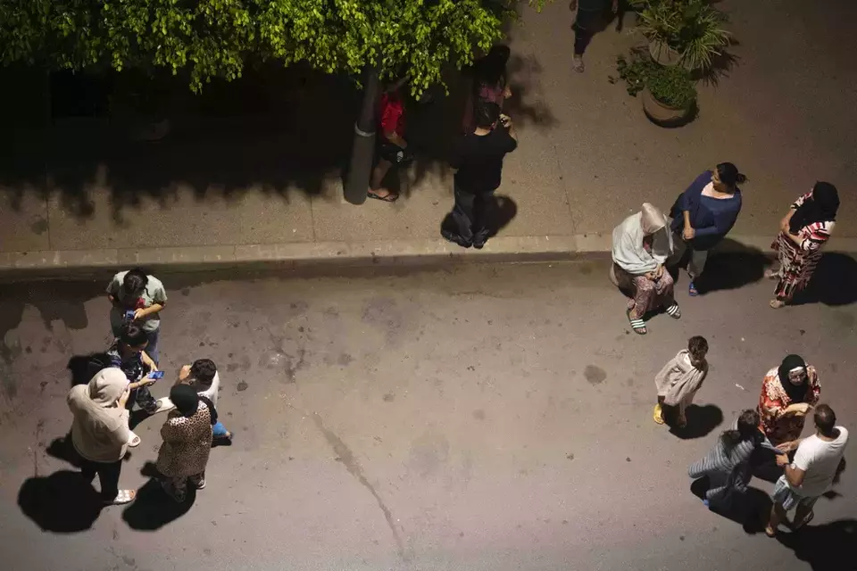 People take shelter and check for news on their mobile phones after an earthquake in Rabat, Morocco, Friday, Sept. 8, 2023. (AP Photo/Mosa