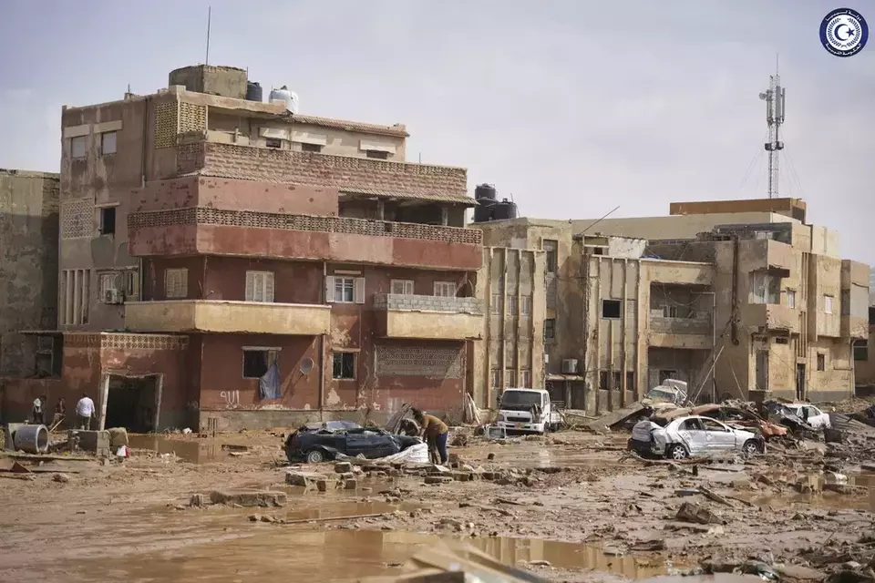 In this photo provided by the Libyan government, cars and rubble sit in a street in Derna, Libya, on Monday, Sept. 11, 2023, after it was flooded by heavy rains. Mediterranean storm Daniel caused devastating floods in Libya that broke dams swept away entire neighborhoods and wrecked homes in multiple coastal towns in the east of the North African nation. (Libyan government via AP)