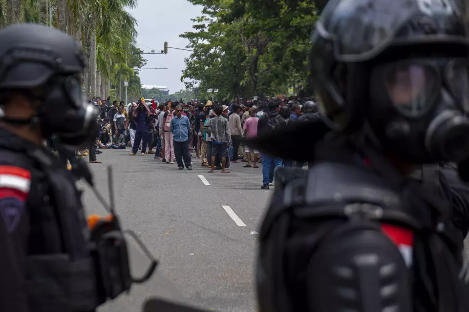 FILE - Riot police stand guard in front of angry residents who oppose relocation from their homes on Rempang Island in Riau Islands province, Monday, Sept. 11, 2023. (Antara Photo/Teguh Prihatna)