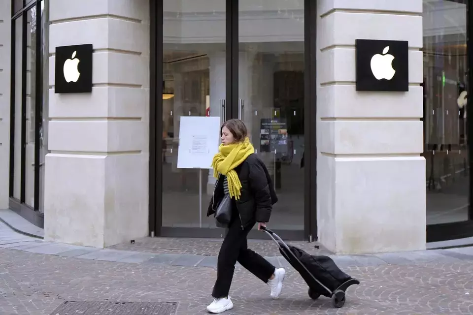 FILE - A woman walks past a closed Apple Store in Lille, northern France, Monday, March 16, 2020.  (AP Photo/Michel Spingler, File)