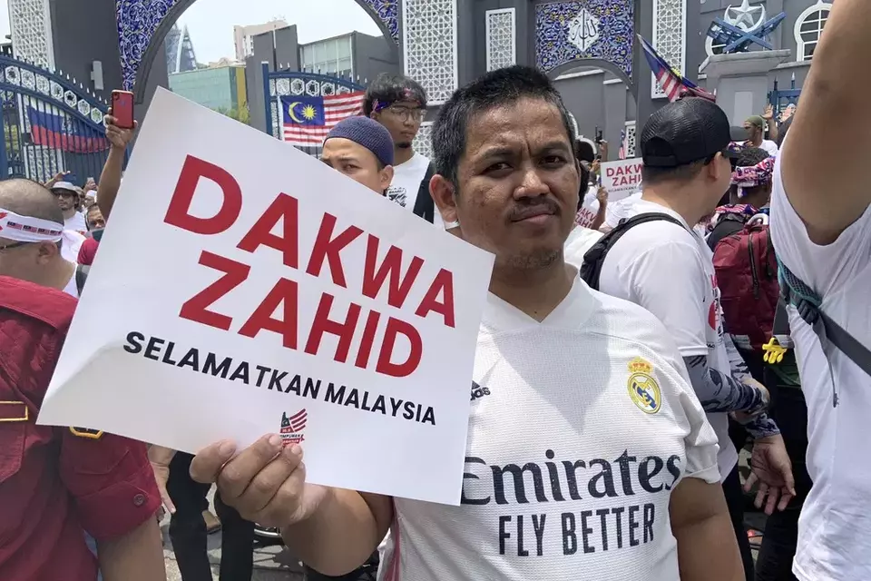 A man holds up a sign with writing reading "Indict Zahid - Save Malaysia" during a protest in Kuala Lumpur, Malaysia, Saturday, Sept. 16, 2023. (AP Photo/Syawalludin Zain)