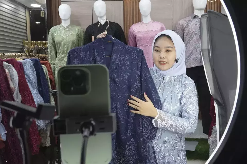A trader conducts live sales via streaming at a store in the Tanah Abang textile market in Jakarta, Indonesia Thursday, Sept. 28, 2023. (AP Photo/Tatan Syuflana)