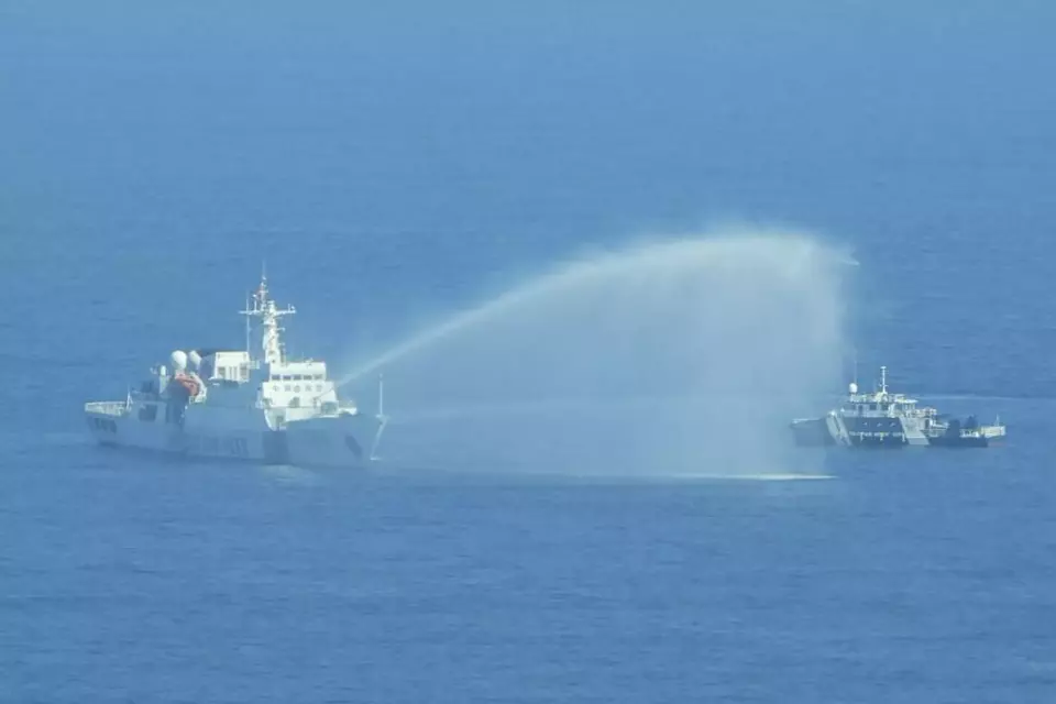 In this photo provided by the Philippine Coast Guard, a Chinese Coast Guard ship, left, uses its water cannons on a Philippine Bureau of Fisheries and Aquatic Resources (BFAR) vessel as it approaches Scarborough Shoal in the disputed South China Sea on Saturday Dec. 9, 2023. (Philippine Coast Guard via AP)