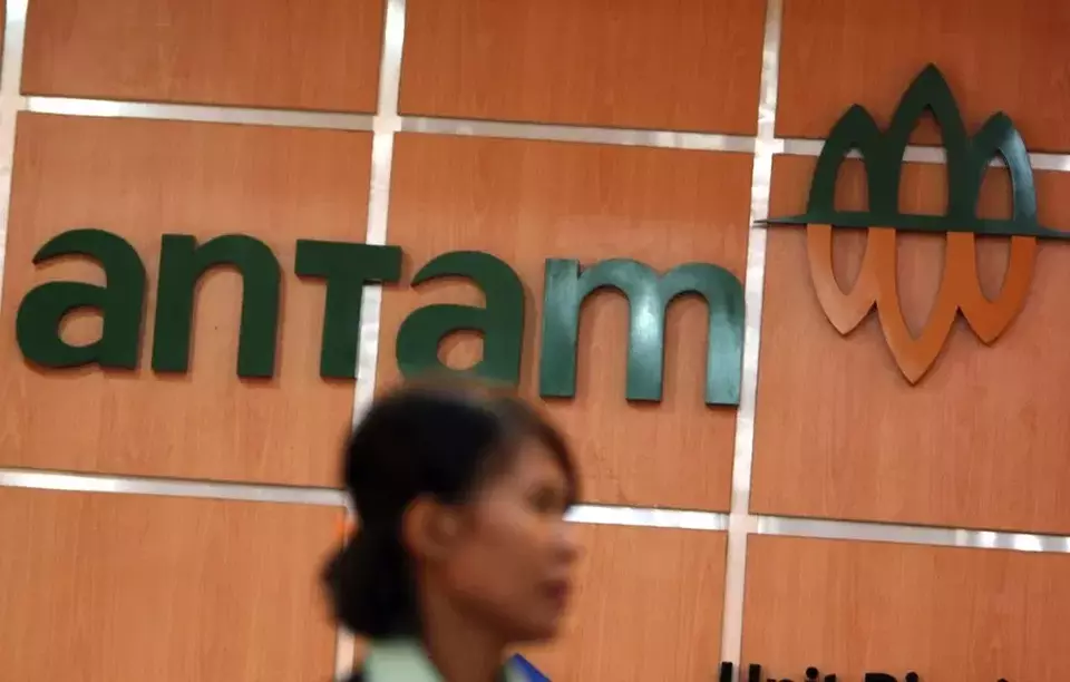 This undated photo shows a woman walking past by the logo of mining giant Antam. (B1 File Photo)
