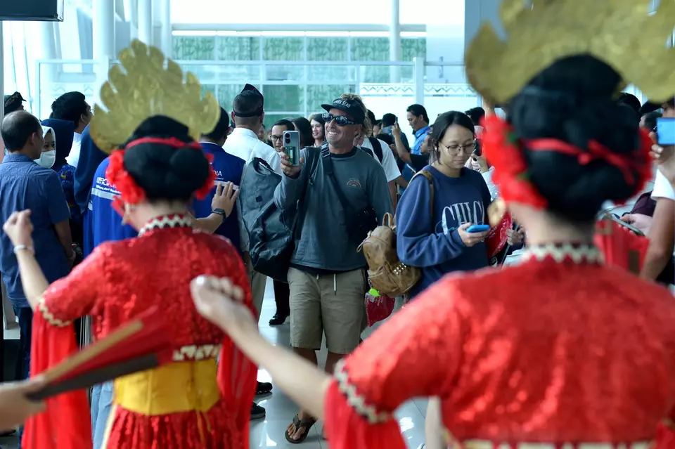 A foreign tourist takes a picture of the traditional dancers in Radin Inten II airport in Lampung on January  17, 2024. (Antara Photo/Fikri Yusuf)
