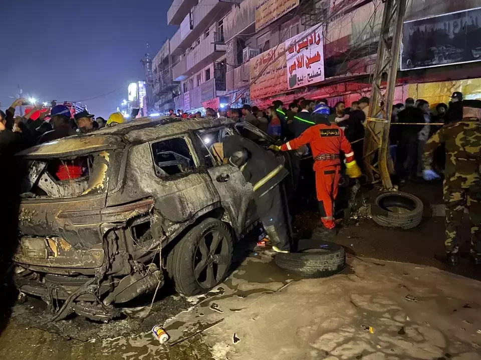 Civil defense members gather at the site of a burned vehicle targeted by a US drone strike in east Baghdad, Iraq, Wednesday, Feb. 7, 2024. (AP Photo/Hadi Mizban)