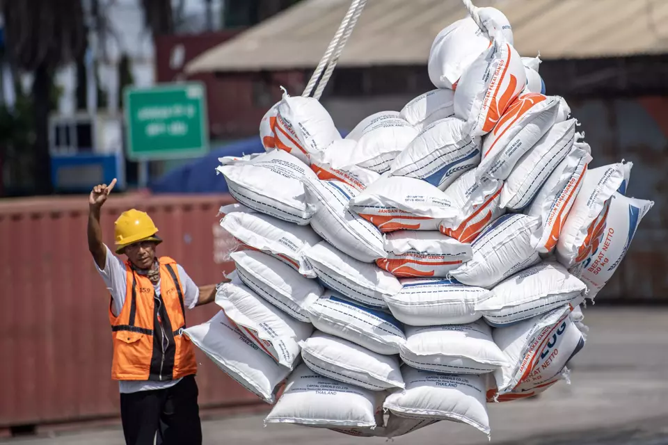 A worker directs as sacks of imported rice from Thailand are lifted at Boom Baru Port in Palembang, South Sumatra, Friday, March 1, 2024. (Antara Photo/Nova Wahyudi)