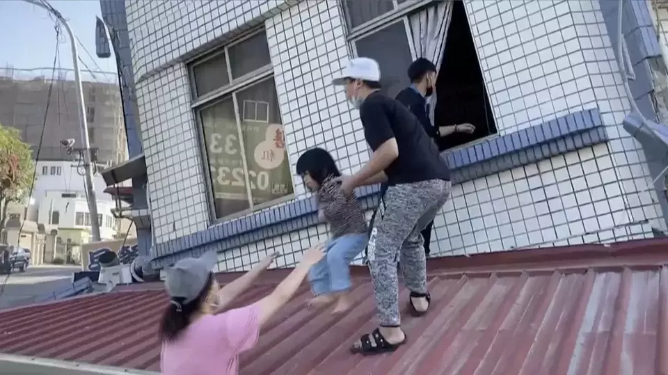 In this image taken from a video footage run by TVBS, residents rescue a child from a partially collapsed building in Hualien, eastern Taiwan on Wednesday, April 3, 2024. (TVBS via AP)