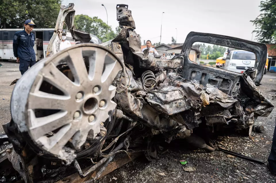 A security guard looks at the wreckage of a Daihatsu Grandmax which was reduced to ashes after a collision with a bus and burst into flame on Cikampek toll road, West Java, Monday, April 8, 2024. (Antara Photo/Bayu Pratama)