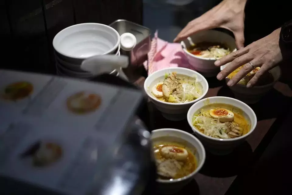 A staff member prepares to serve noodles for participants of Tokyo Ramen Tours at Syuuichi, which means "once a week," featuring curry-flavored ramen, at Shibuya district on April 2, 2024, in Tokyo. (AP Photo/Eugene Hoshiko)
