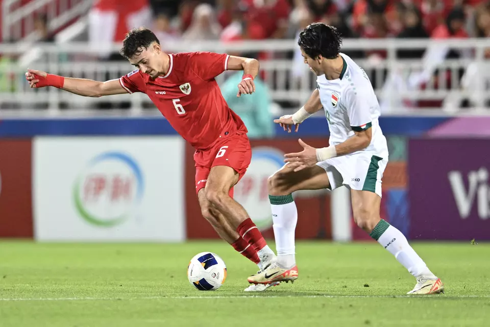 Indonesia U-23's Ivar Jenner (left) dribbles past Iraq U-23's Karrar Mohammed Ali (right) during the AFC U-23 Asian Cup third-place playoff in Doha, Qatar,
